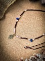 Choker z lapis lazuli i perłami hodowlanymi wykonany techniką mikromakramy. Ręcznie robiony naszyjnik z Hamsą i złotymi dodatkami, talizman z kamieni naturalnych dla kobiet ceniących naturę i duchowość.