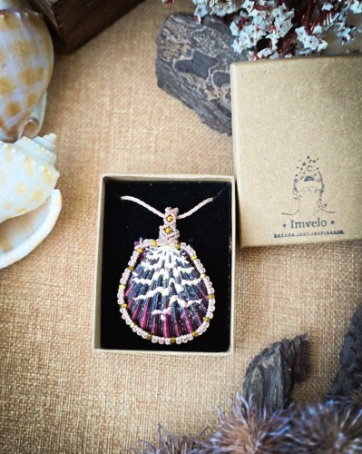 Ręcznie wykonany naszyjnik z naturalną muszlą w technice mikromakramy. Autorska biżuteria handmade IMVELO z brazylijskiego sznurka Linhasita, złocone hematyty, regulowana długość i niepowtarzalny wzór muszli.