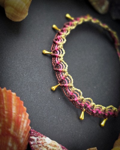 Ręcznie pleciona bransoletka na kostkę z mikromakramy wykonana ze sznurka Linhasita w kolorach brązowym, beżowym, różowym i złotym. Regulowana biżuteria boho handmade do letnich stylizacji.