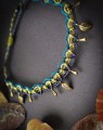 Ręcznie pleciona bransoletka na kostkę z mikromakramy wykonana ze sznurka Linhasita w kolorach granatowym, morskim, oliwkowym i złotym. Regulowana biżuteria boho handmade z zawieszkami w kolorze antycznego brązu.