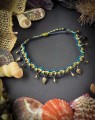 Bransoletka na kostkę boho z regulacją długości wykonana techniką mikromakramy. Autorska biżuteria handmade ze sznurka Linhasita z ozdobnymi zawieszkami w kolorze antycznego brązu.